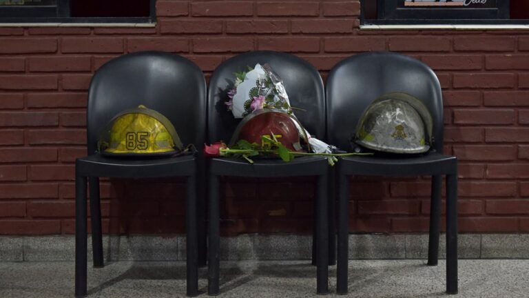 Los cascos de los tres bomberos en la puerta del destacamento, con la ofrenda floral para los fallecidos.