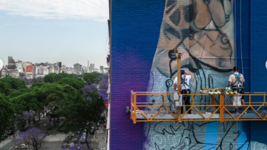 Colgados de andamios, así trabaja el equipo del artista Martín Ron sobre el mural de LIones Messi en la avenida 9 de Julio.